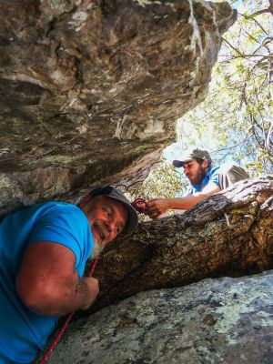 Me tightly wedged within the crack as I attempt to get over the large pine tree root that blocks the way. My son Tyler is above and has fabricated a slip loop to aid in my ascent (Photo by John Forbes) 
