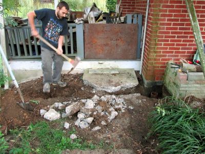 Tyler helping to bust through the sidewalk so we can remove the old clay gutter drain pipe. 
